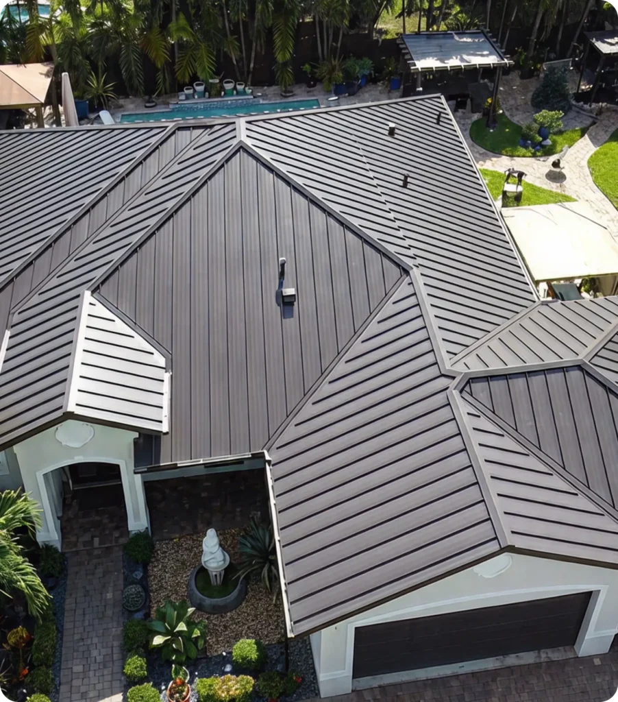 Aerial view of a Miami, FL home with a gray metal roof installed by 7Roofing, surrounded by palm trees, landscaping, and a backyard pool.